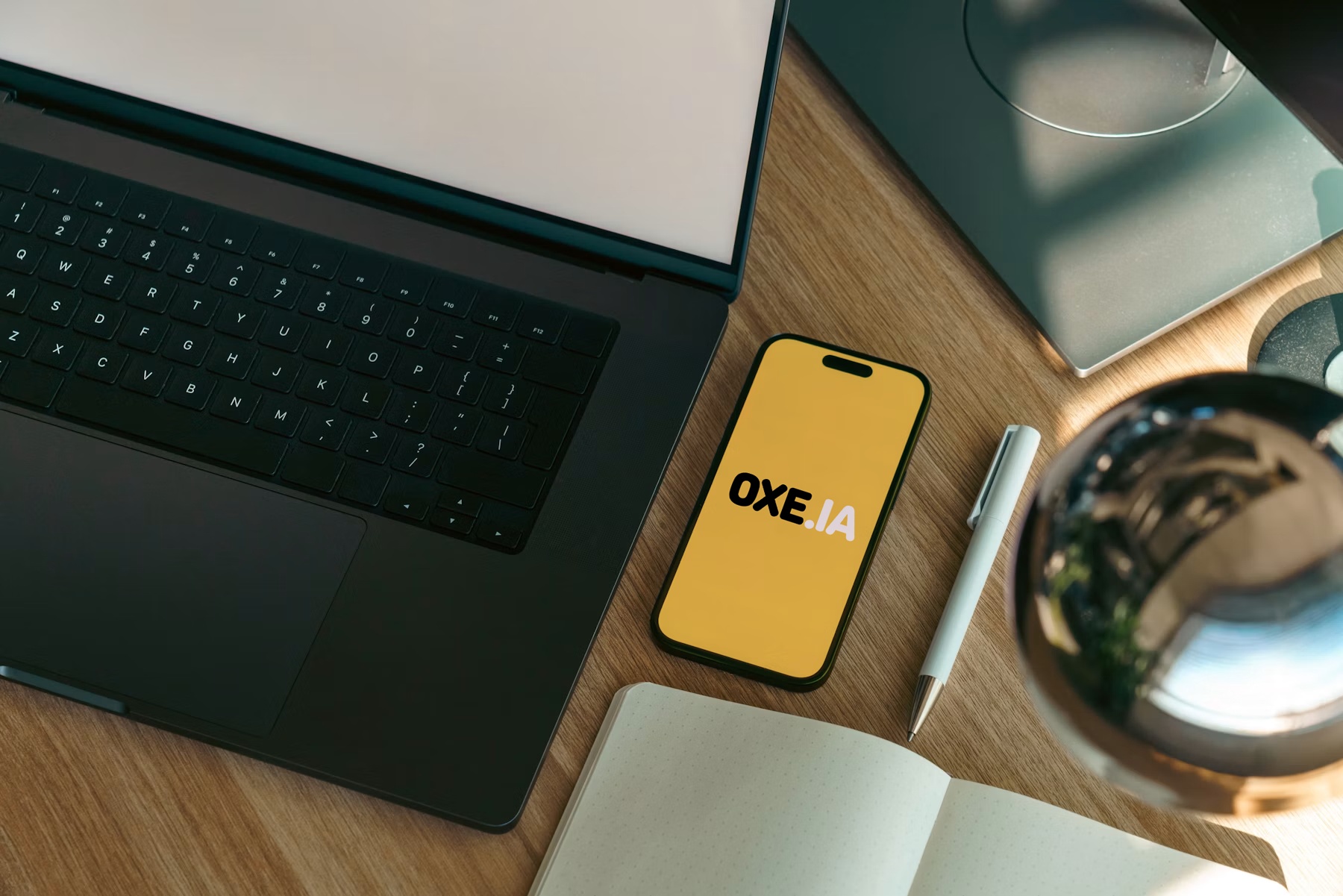Mesa de trabalho com notebook, celular e caderno